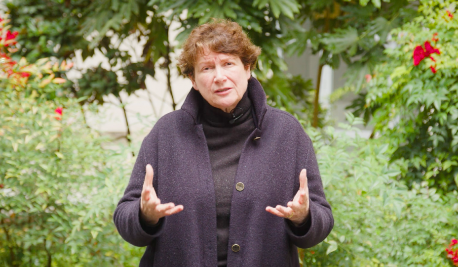 Christine de Neville, présidente de PEFC France est dans un jardin vert avec des fleurs rouges